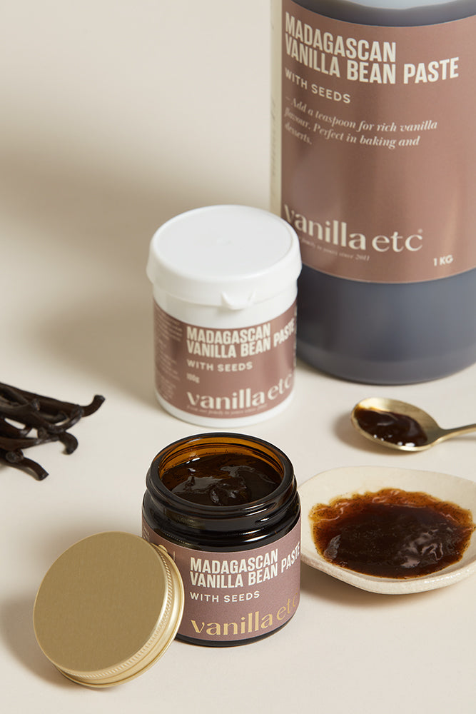 Bottle, jar  and tub of Vanilla bean paste with open container and silver spoon showing consistency