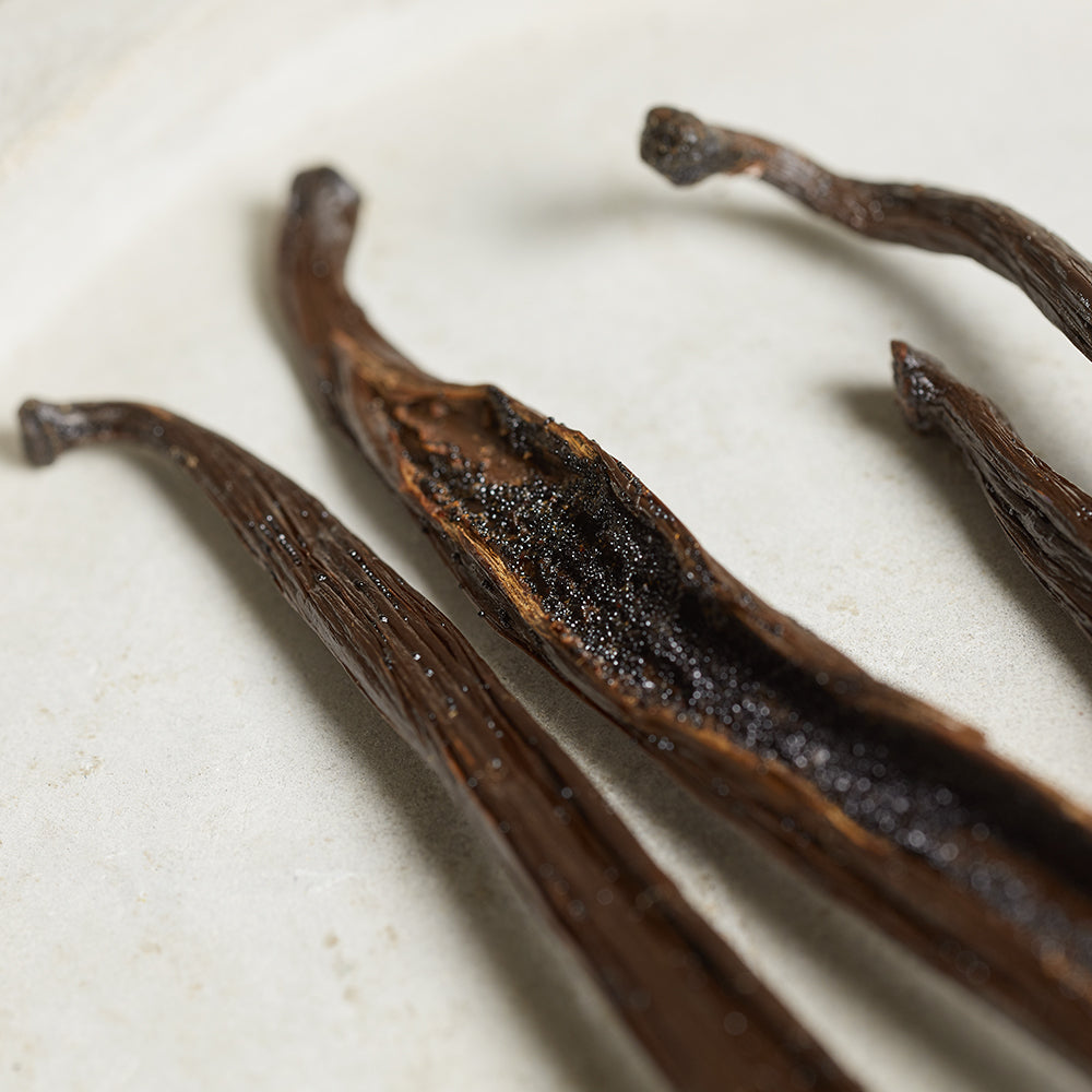 Close-up of vanilla beans showing the seeds within, on a light background