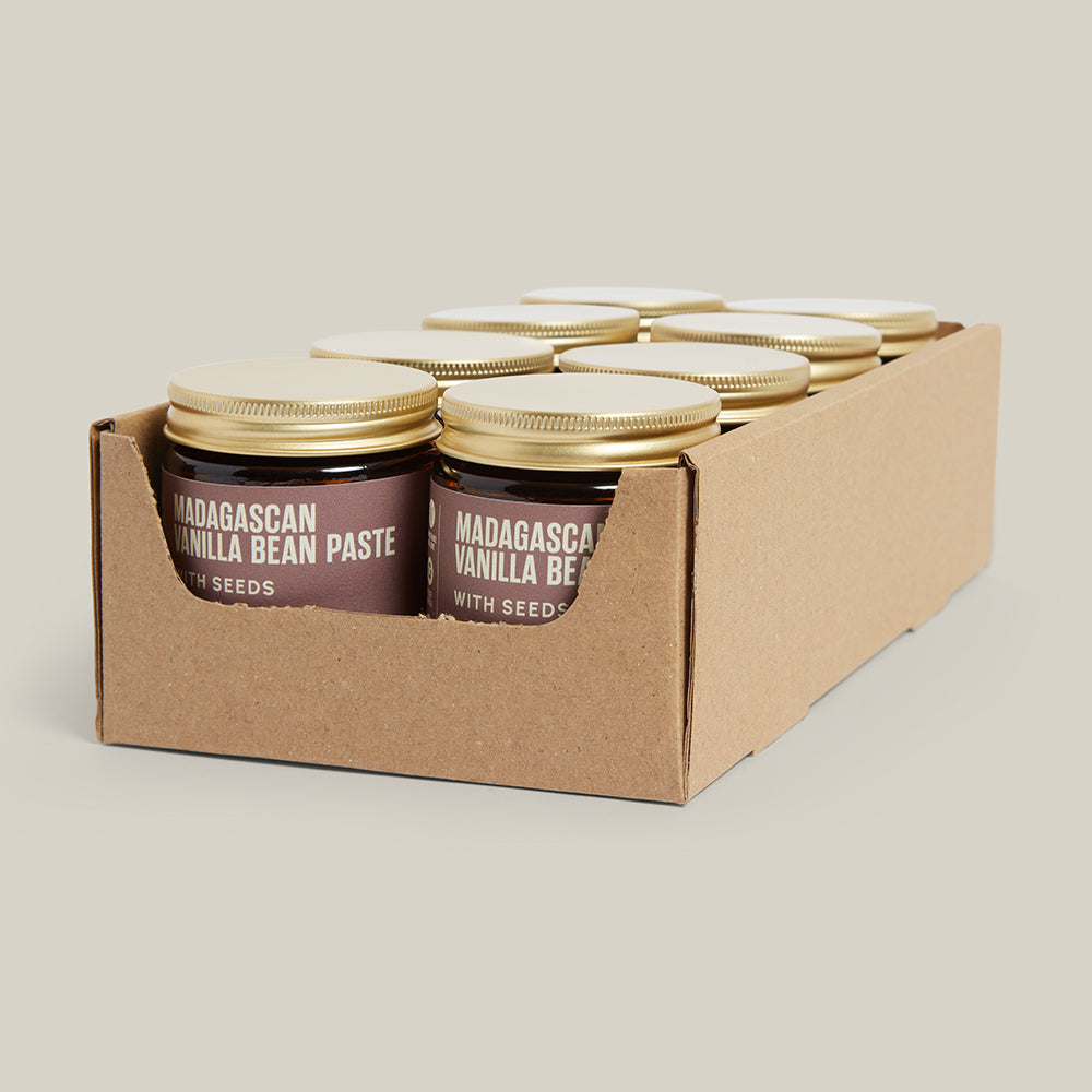 Carton with 8 jars of Madagascar vanilla bean paste on a cream background