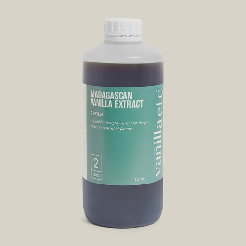 Bottle of Vanilla Extract with a white cap on a beige background